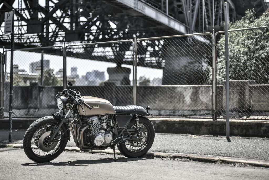 brown standard motorcycle near wire fence during daytime